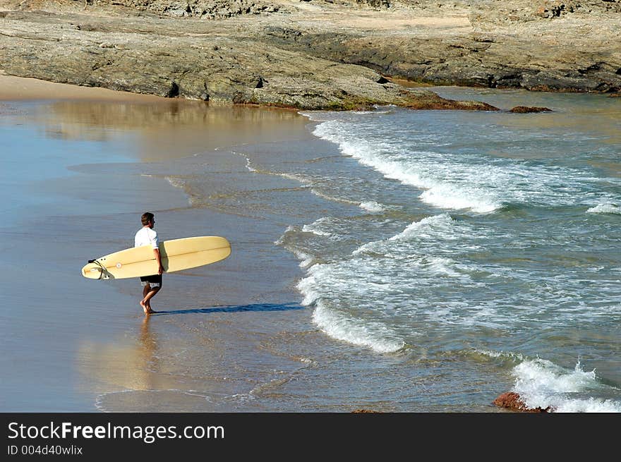 Guy heading out to the waves for a surf. Guy heading out to the waves for a surf