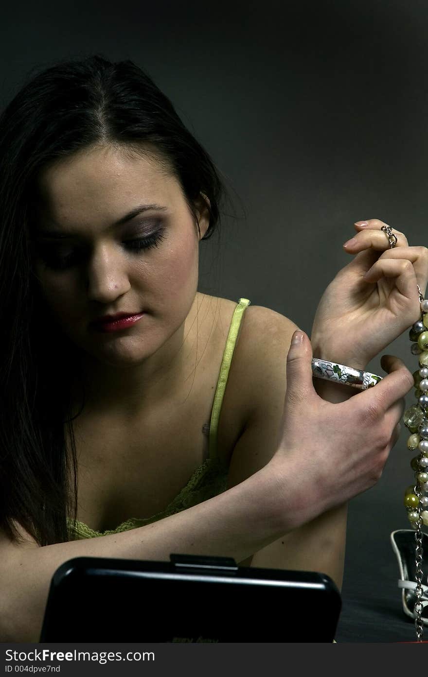 Young pretty woman putting on her accessories, getting ready for a party. Young pretty woman putting on her accessories, getting ready for a party.