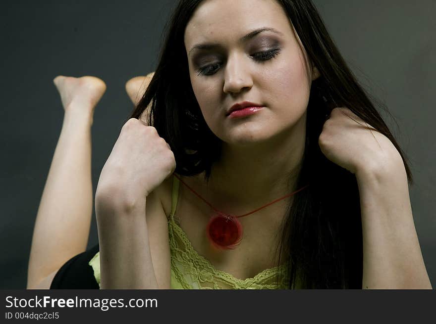 Young woman looks in a small mirror, checking on her face with a little vanity in her expression