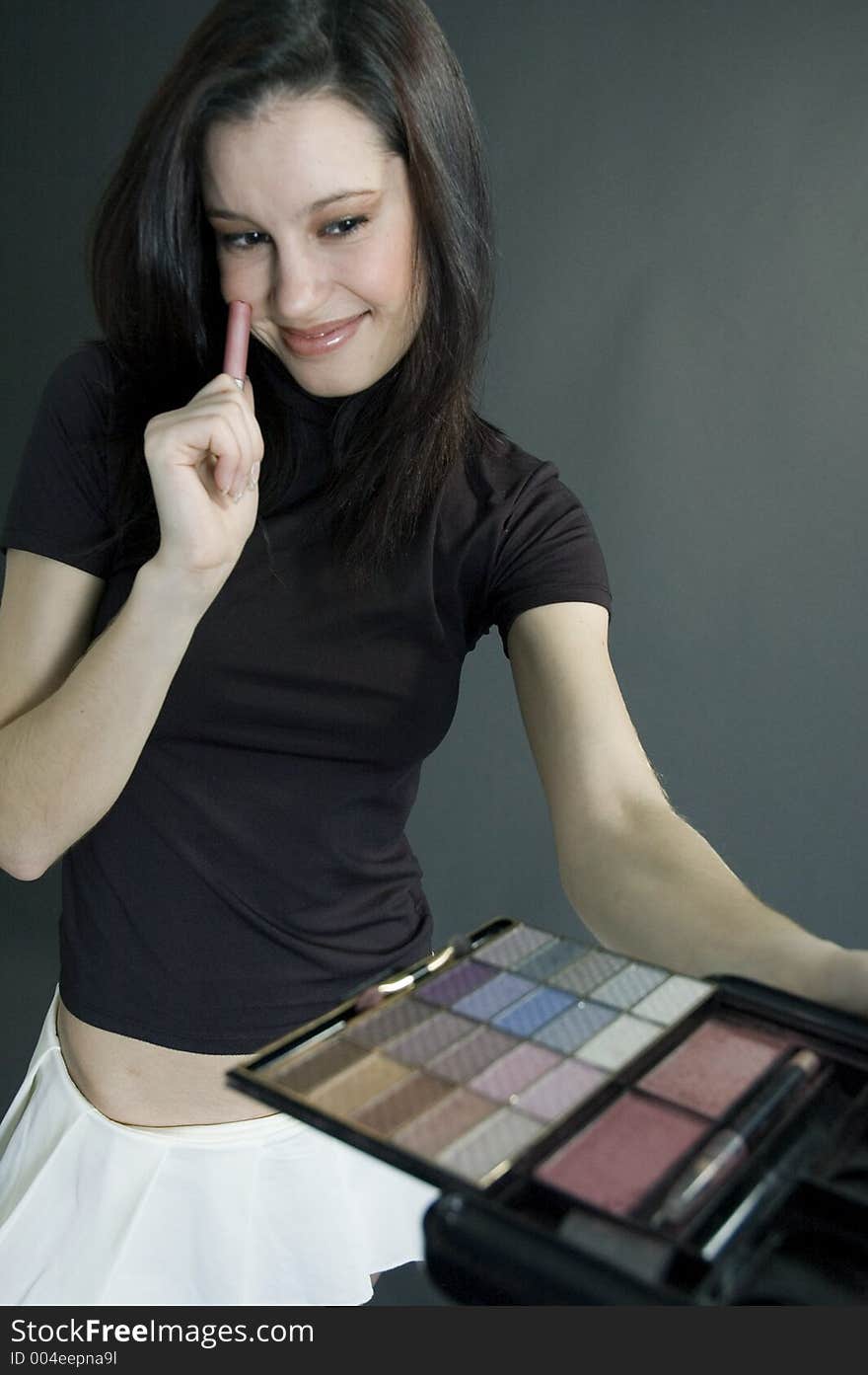 Attractive young woman holding some make-up and smiling with confidence. Attractive young woman holding some make-up and smiling with confidence