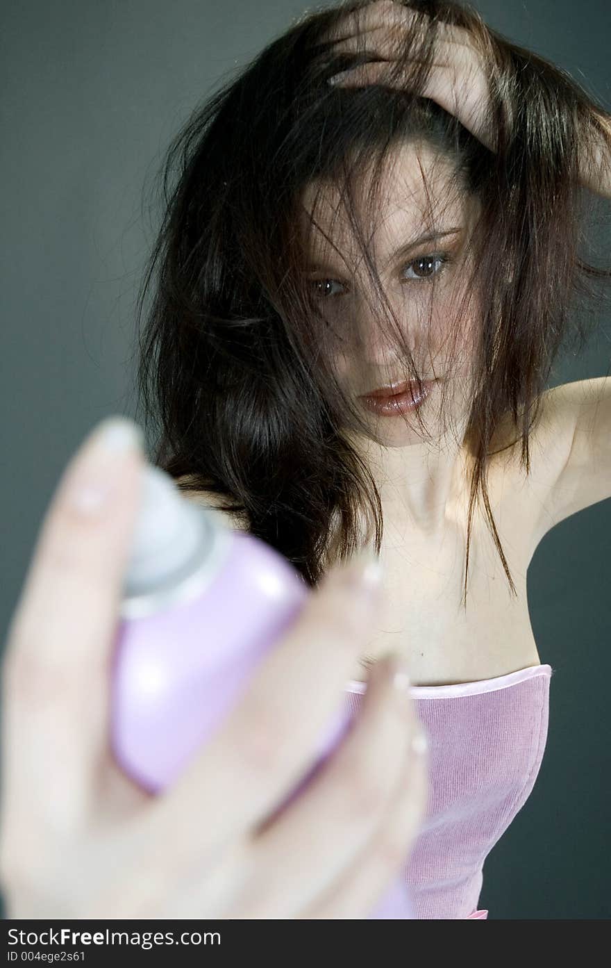 Young woman using hair spray