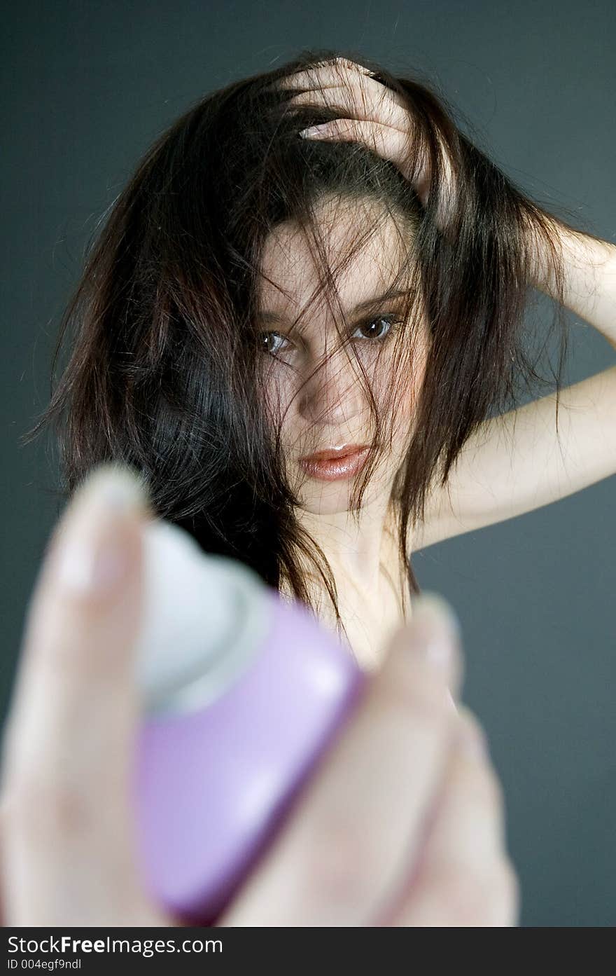 Young woman using hair spray