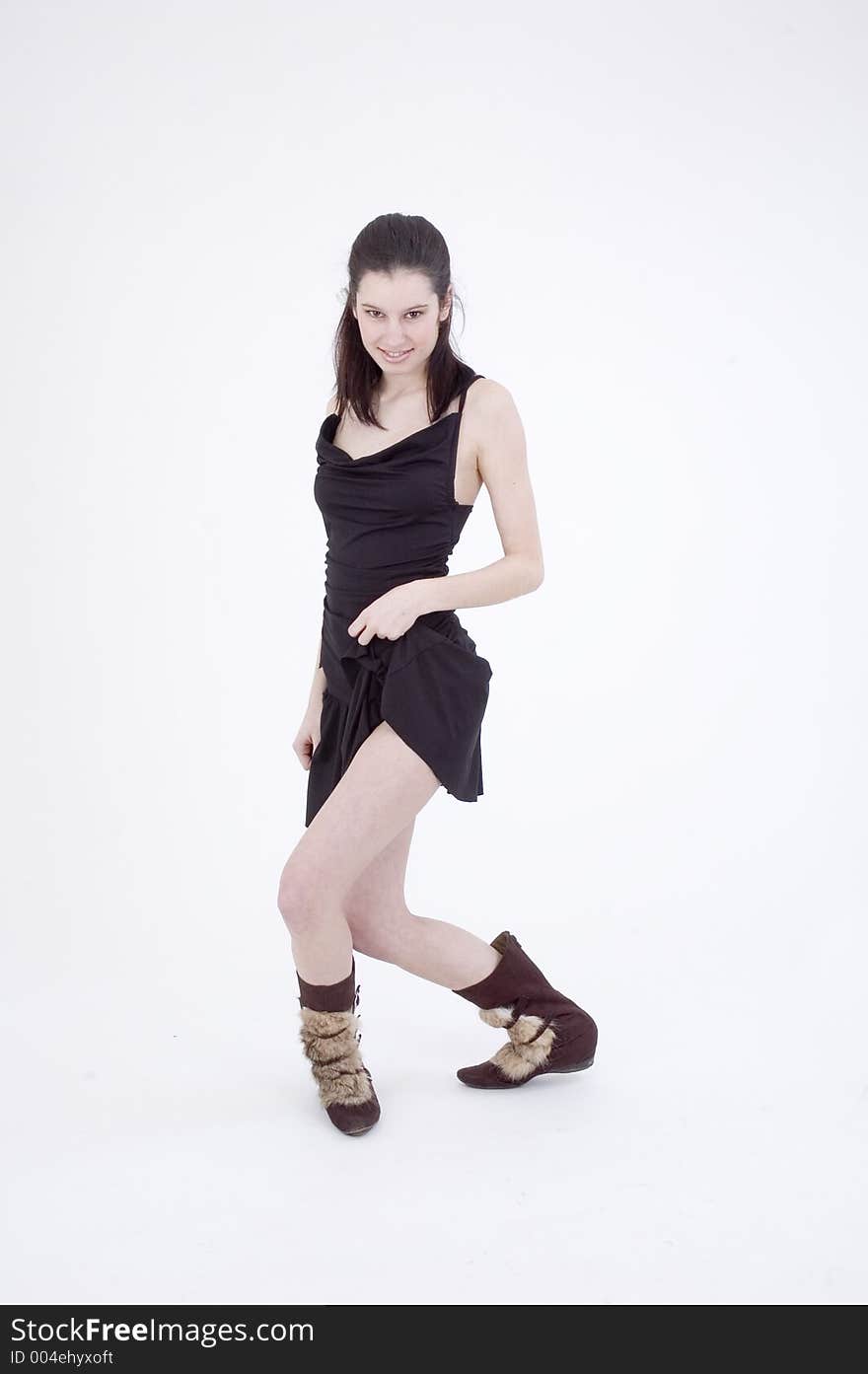 young dancer, in black short skirt and trendy fur boots, making a sensual move on a white studio background. young dancer, in black short skirt and trendy fur boots, making a sensual move on a white studio background