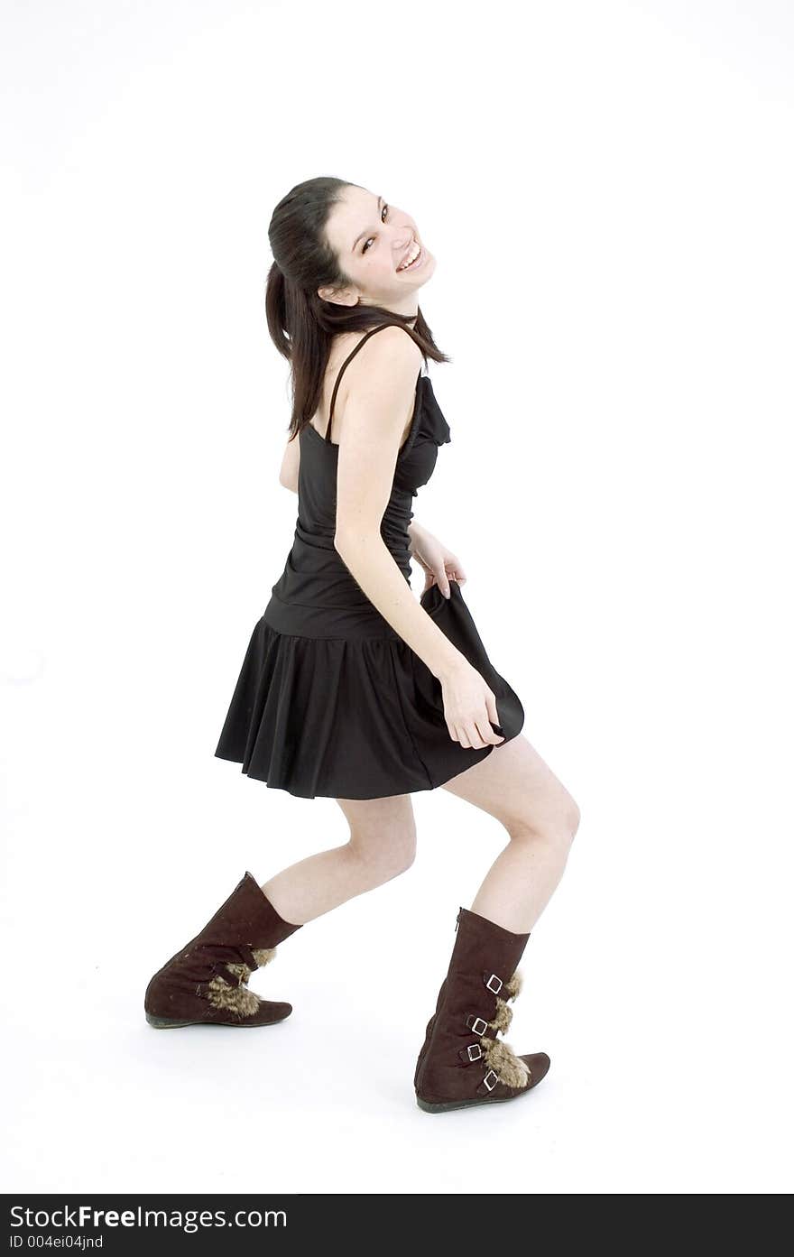 young brunette, in black short skirt and trendy fur boots, dancing on a white studio background. young brunette, in black short skirt and trendy fur boots, dancing on a white studio background