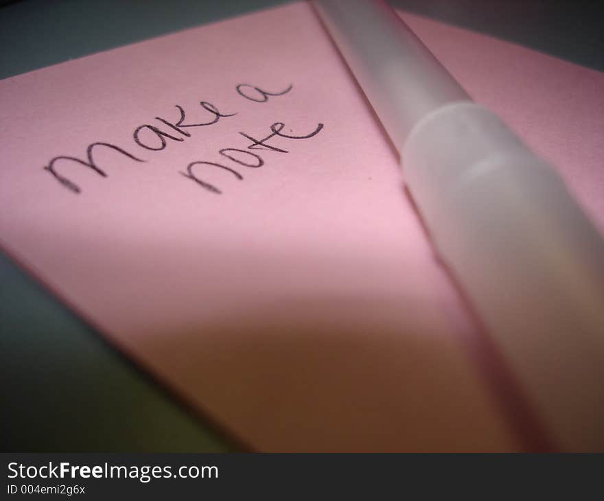 A pink Post-It Note with an ink pen laying on top. A pink Post-It Note with an ink pen laying on top.