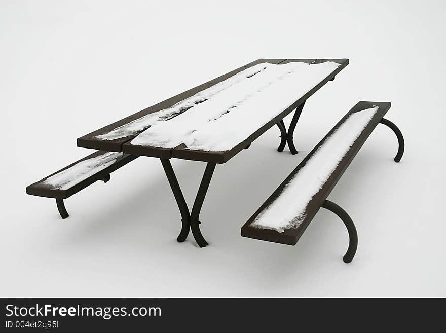 Snow-covered picnic table surrounded by pristine snow. Snow-covered picnic table surrounded by pristine snow.