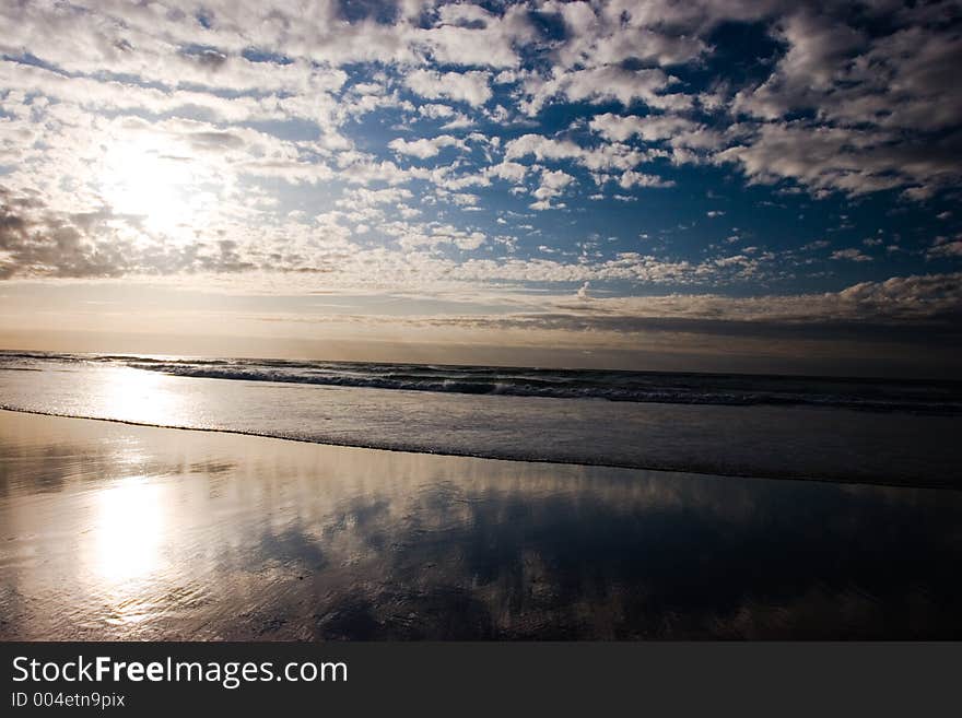 An expansive beach with small waves and a dramatic deep blue sky with clouds. An expansive beach with small waves and a dramatic deep blue sky with clouds