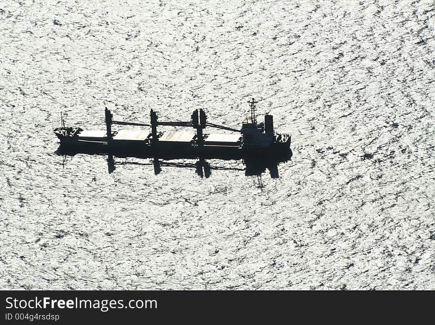 Bulk carrier cargo boat on silver sea, backlit