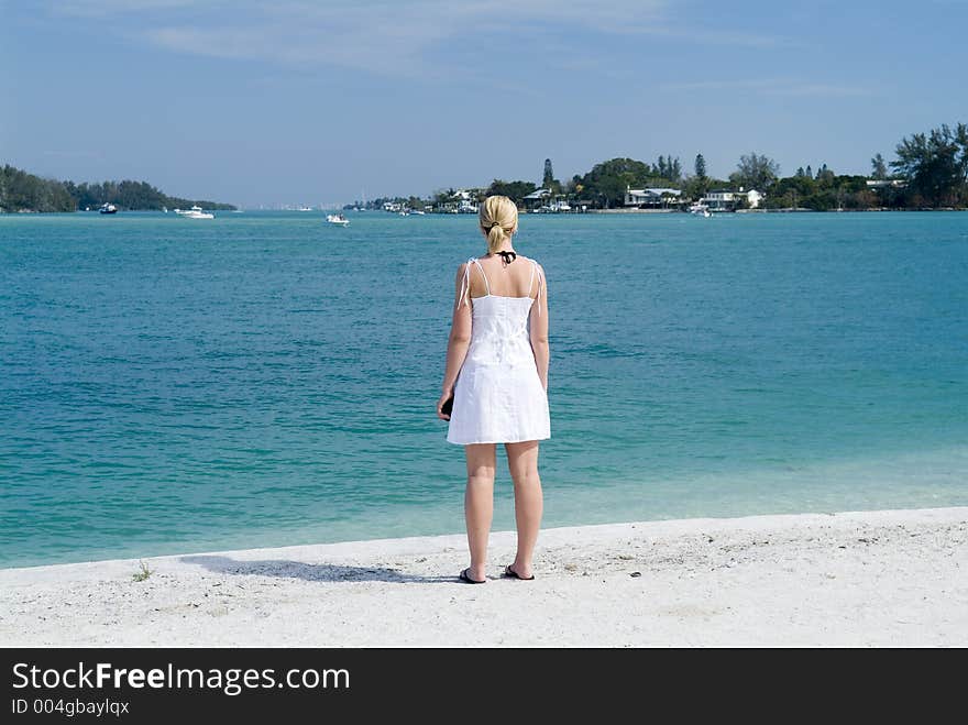 Woman in white dress looking out to sea. Woman in white dress looking out to sea