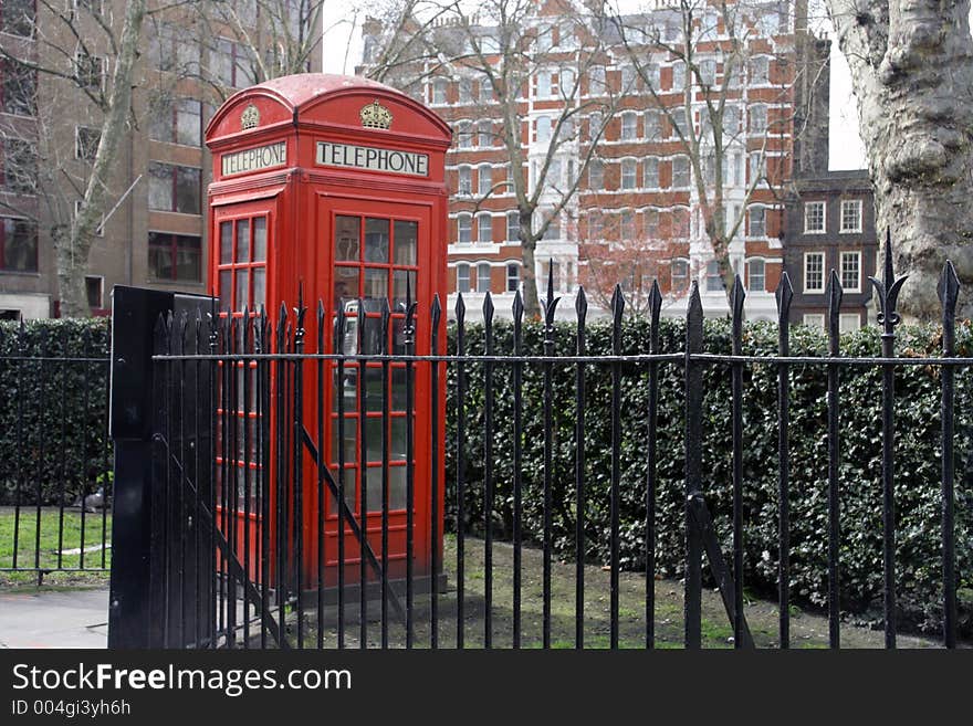 A traditional london phone box behind railings. A traditional london phone box behind railings