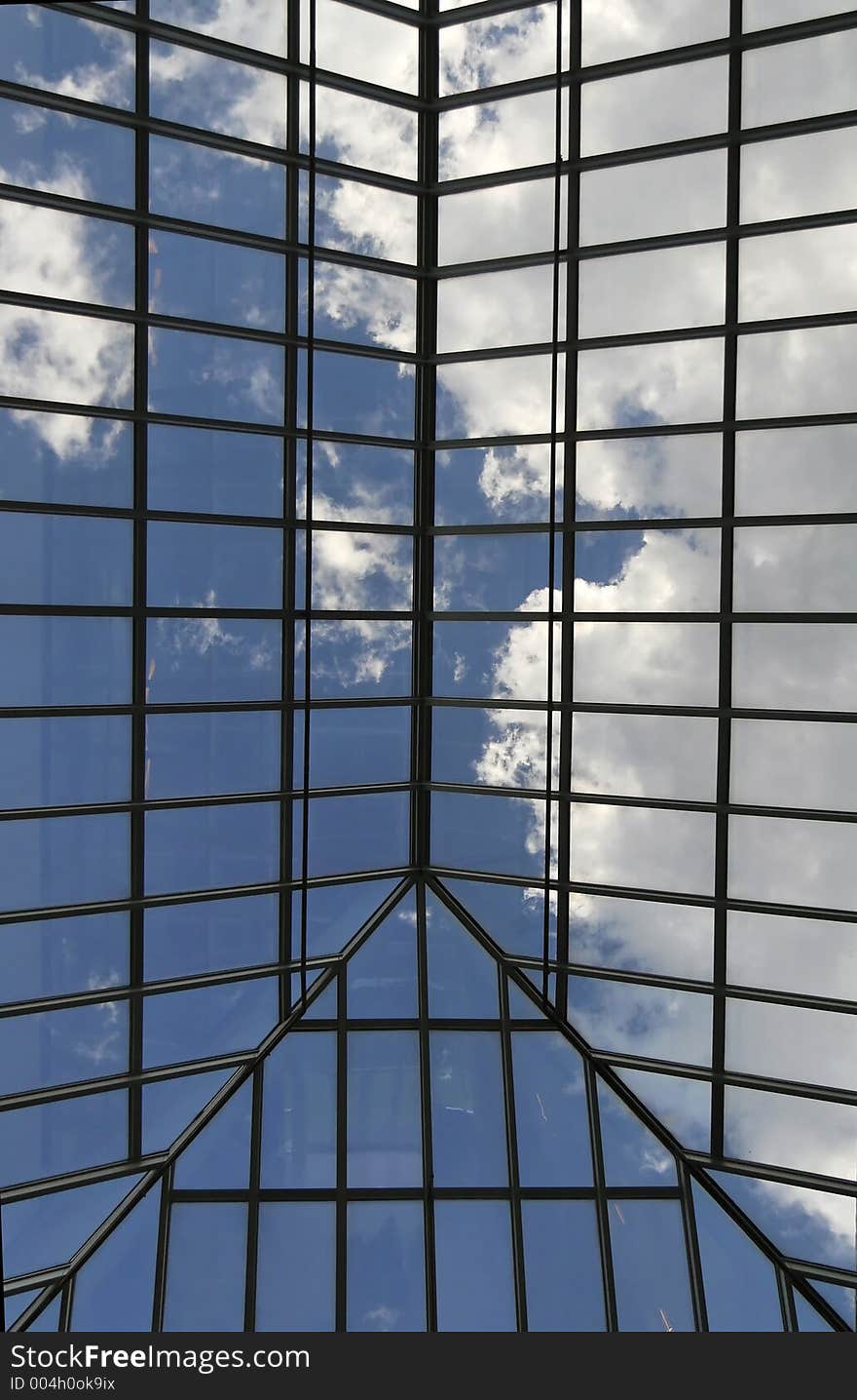 Blue sky with clouds viewed through glass roof of an atrium