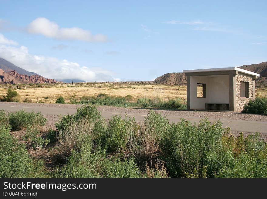 A road through the mountains with a bus stop along the side. A road through the mountains with a bus stop along the side