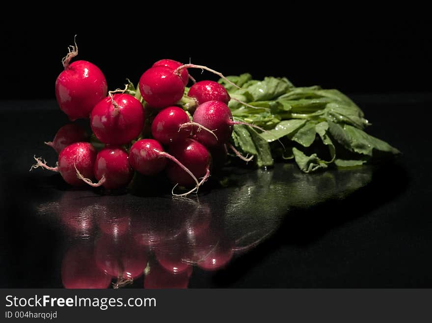 Fresh red radish spinkled with water on a glass surface