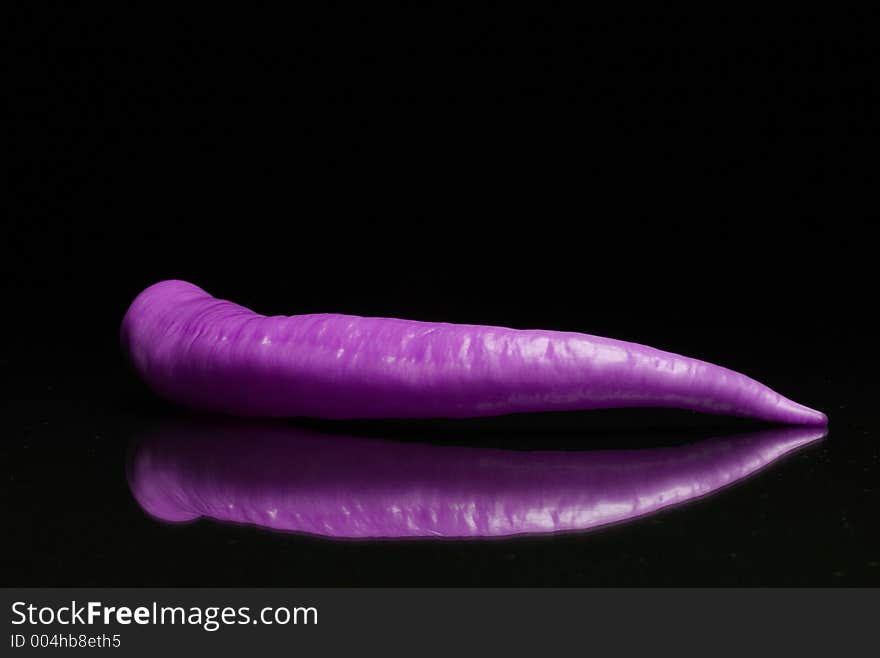 Violet paprika with reflex on black background