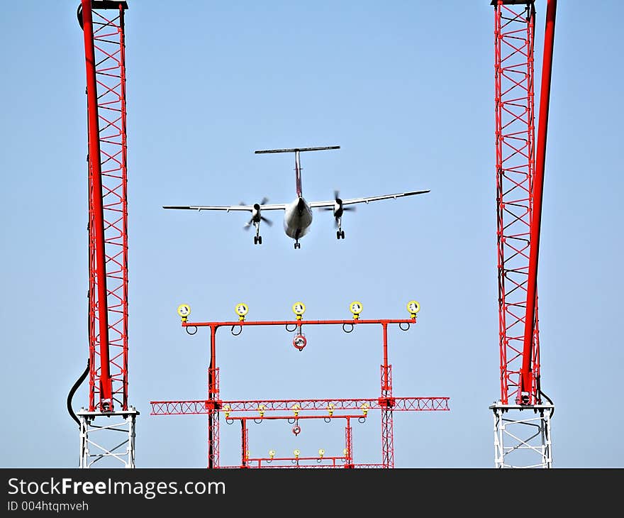 Plane landing. Private jet. Framed into the airport landing navigation lighting towers. Plane landing. Private jet. Framed into the airport landing navigation lighting towers.