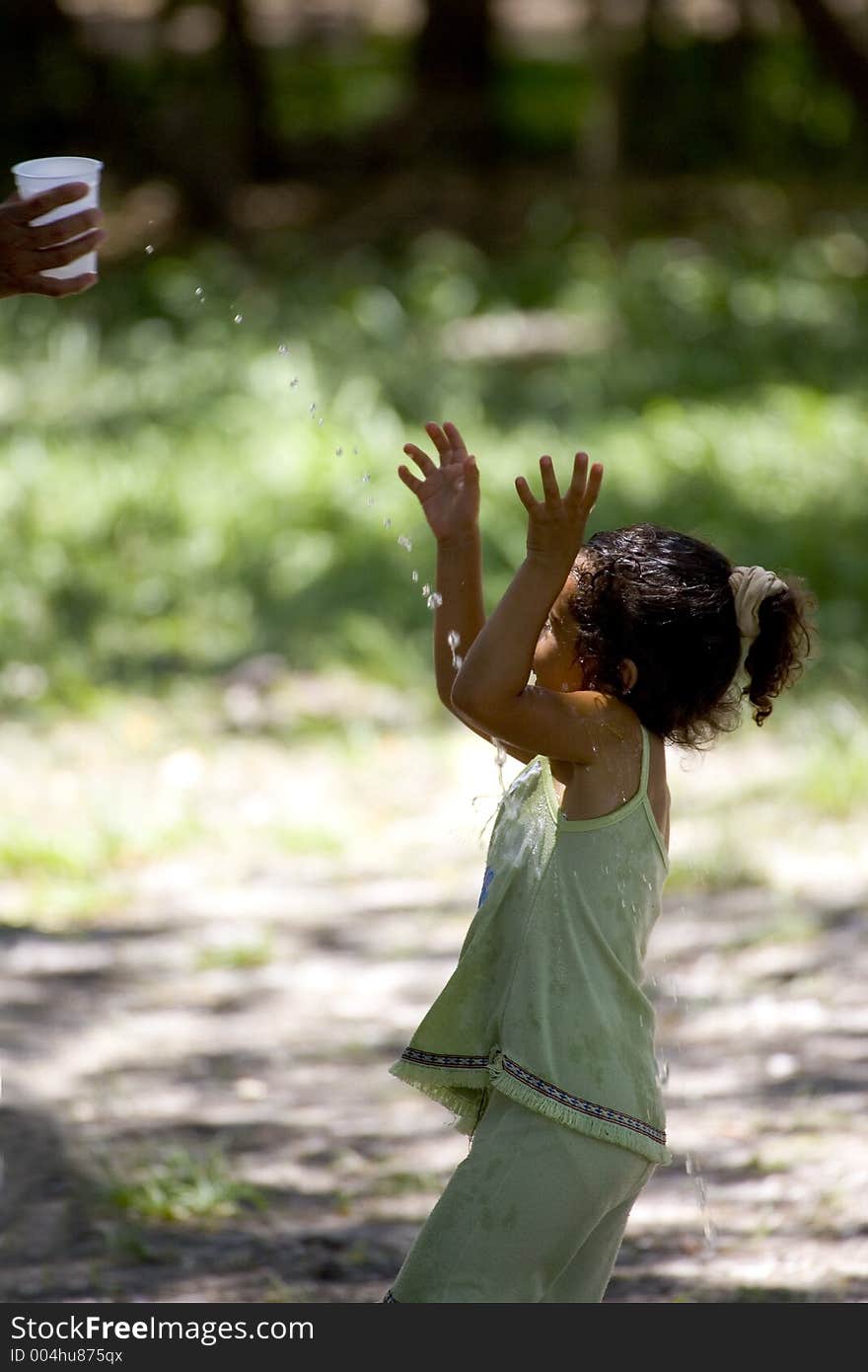 A girl gets water splashed on her in Central America. A girl gets water splashed on her in Central America