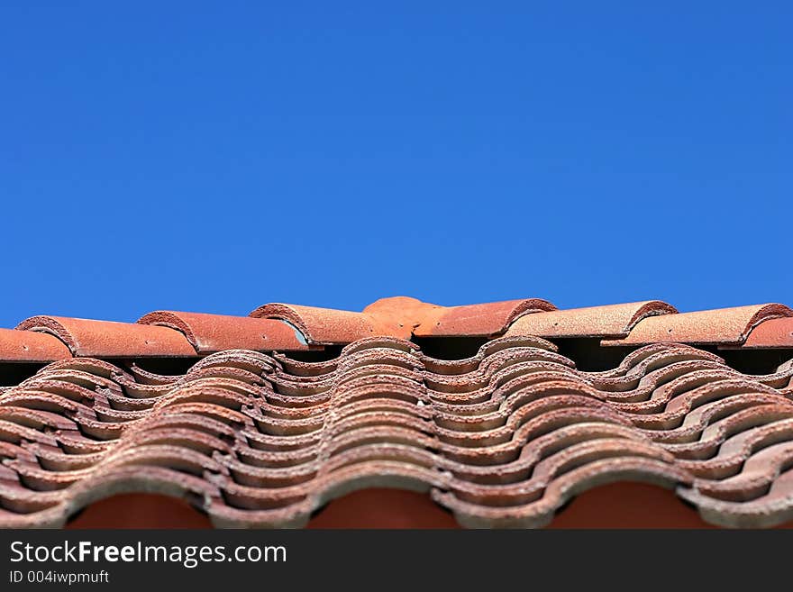 Orange roof tiles radiate from a point with blue sky above. Orange roof tiles radiate from a point with blue sky above