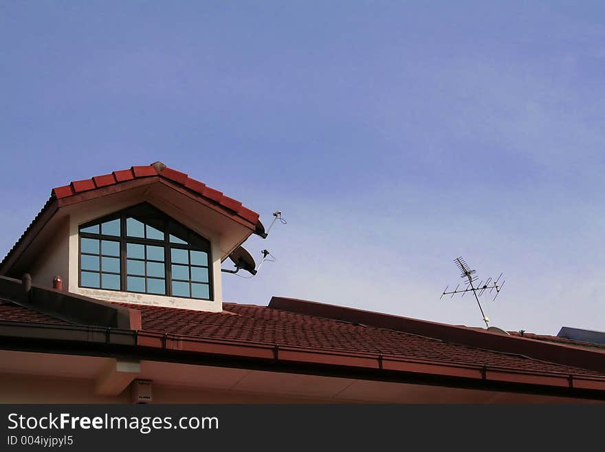 Roof of a house, skylight and television antenna against the sky