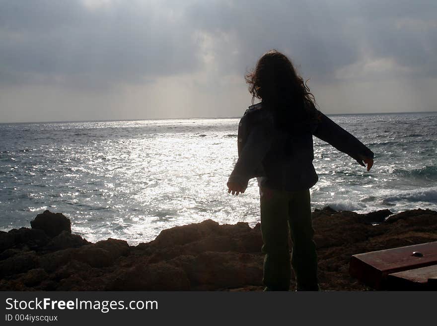 Young girl by the rocky coast after the rain. Young girl by the rocky coast after the rain