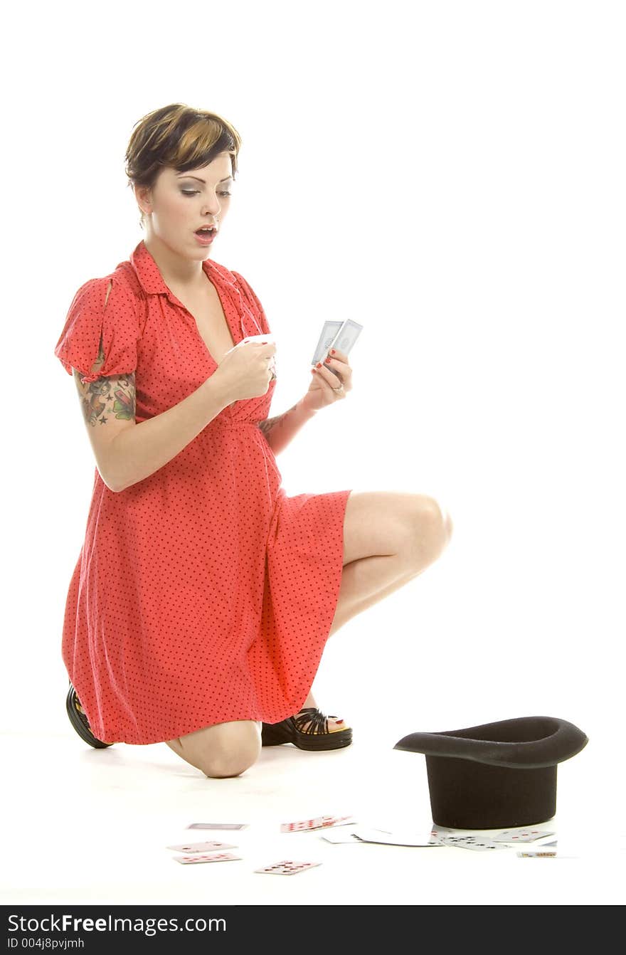 young actress with tattoos, a red girlish dress, poses different postures and expressions for an audition, with playing cards and a big black hat, over a white background. young actress with tattoos, a red girlish dress, poses different postures and expressions for an audition, with playing cards and a big black hat, over a white background