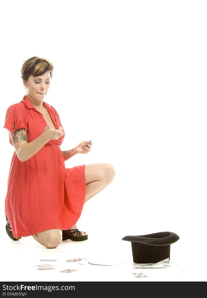 young actress with tattoos, a red girlish dress, poses different postures and expressions for an audition, with playing cards and a big black hat, over a white background. young actress with tattoos, a red girlish dress, poses different postures and expressions for an audition, with playing cards and a big black hat, over a white background