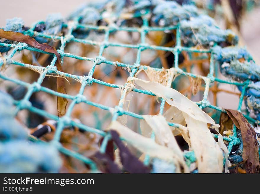 Abandoned lobster trap on an English beach. Random seaweed and litter taggled in with the mesh netting. Abandoned lobster trap on an English beach. Random seaweed and litter taggled in with the mesh netting.