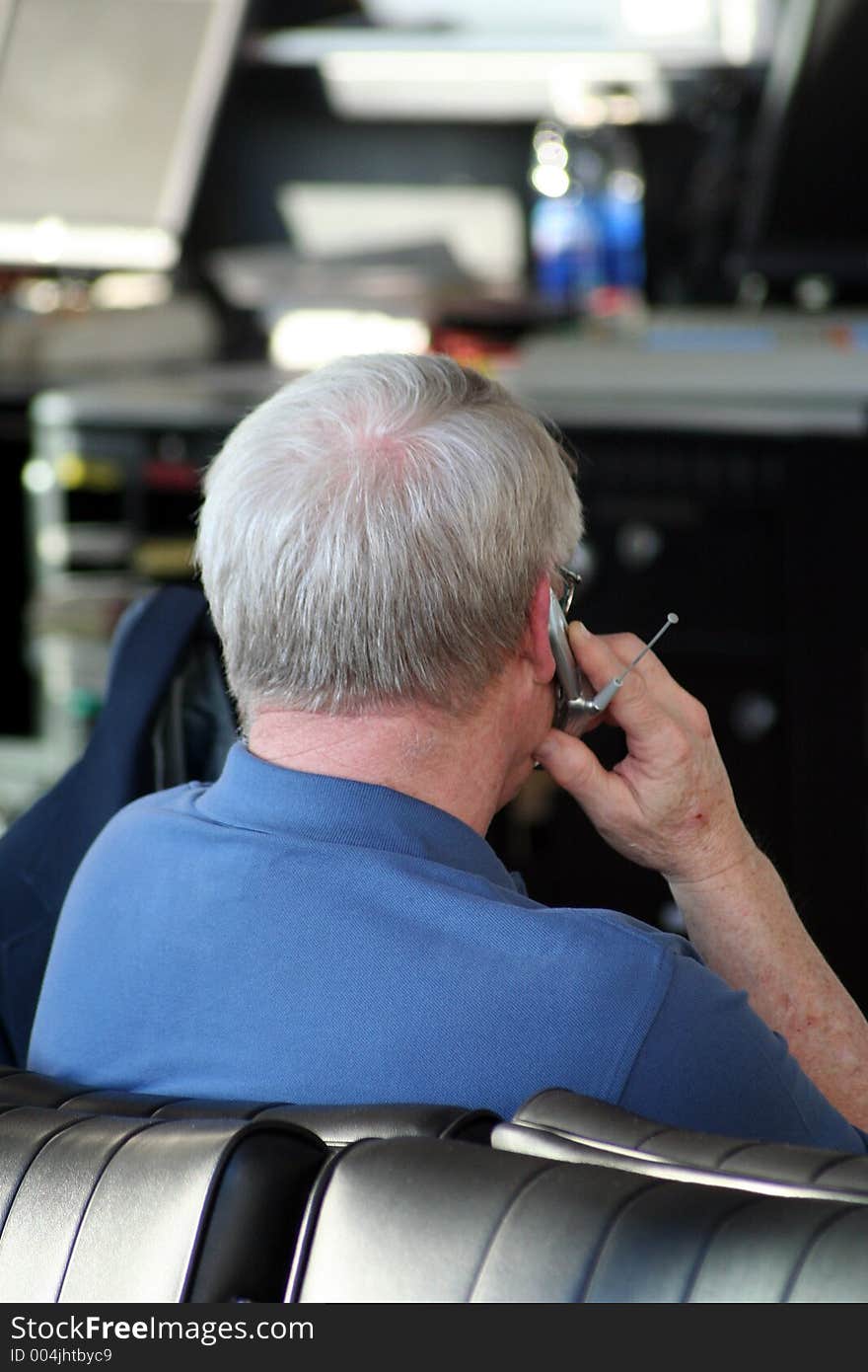 A senior male uses his cell phone to call while waiting for his airplane to board. A senior male uses his cell phone to call while waiting for his airplane to board