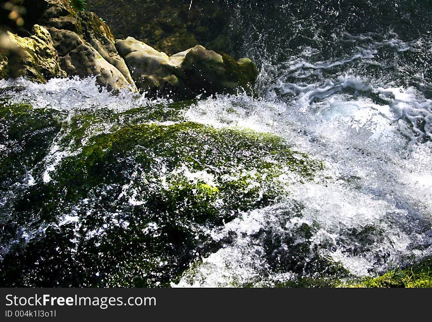 Small waterfall rushing over rock edge into a small lagoon. Small waterfall rushing over rock edge into a small lagoon.