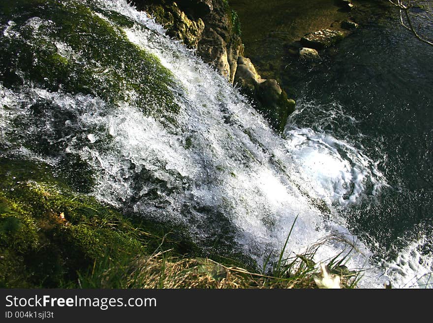 Small waterfall rushing over rock edge into a small lagoon. Small waterfall rushing over rock edge into a small lagoon.