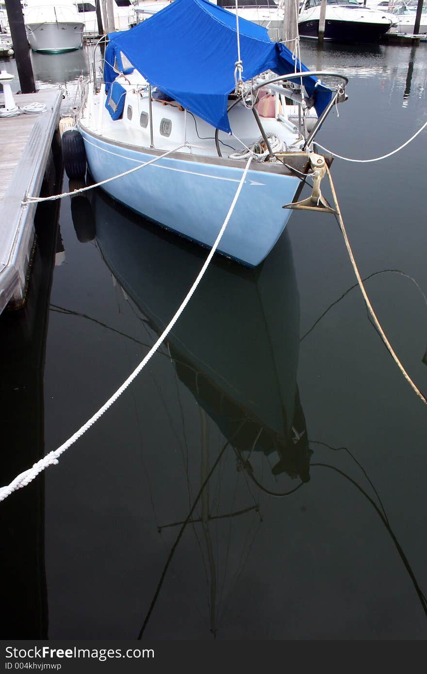 A light blue sailboat is tied up in a marina. A light blue sailboat is tied up in a marina