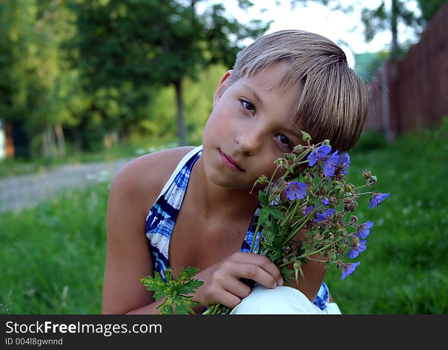 The girl sitting with a bouquet of field flowers. The girl sitting with a bouquet of field flowers.