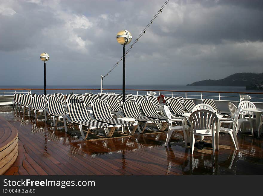 White chairs on recently washed deck of cruise ship on a cloudy morning. White chairs on recently washed deck of cruise ship on a cloudy morning