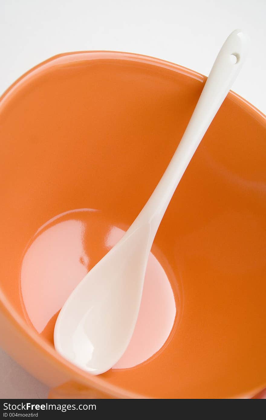 Orange cup with white spoon. Orange cup with white spoon