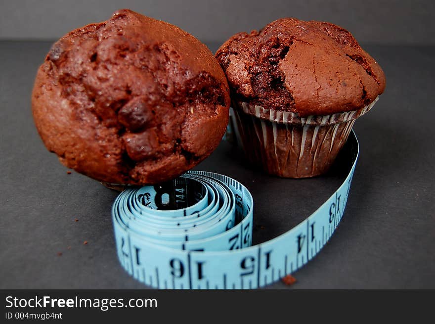 This is an image of two chocolate muffins and a measuring tape. This is a metaphor for dieting. (Please let me know where the image will be used by leaving a message in the Comments Section/See Portfolio). This is an image of two chocolate muffins and a measuring tape. This is a metaphor for dieting. (Please let me know where the image will be used by leaving a message in the Comments Section/See Portfolio)