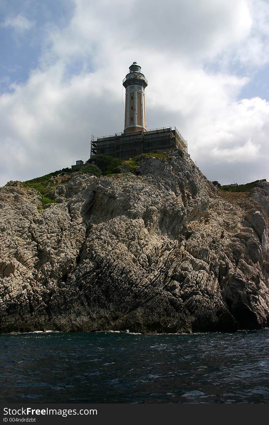 Small lighthouse sitting atop large cliff. Small lighthouse sitting atop large cliff