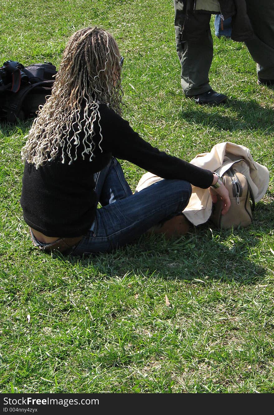 Girl sitting on grass listening to an open-air concert