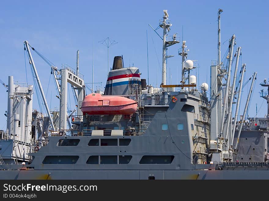 A cargo vessel with a modern fire-proof lifeboat hanging from its side. A cargo vessel with a modern fire-proof lifeboat hanging from its side.