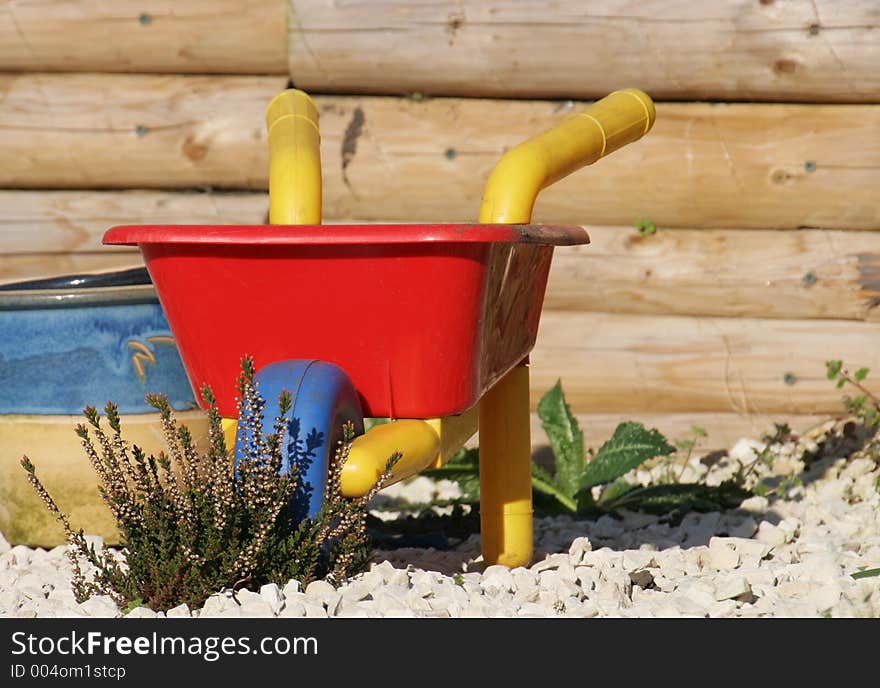 A childs wheel barrow outside in spring. A childs wheel barrow outside in spring