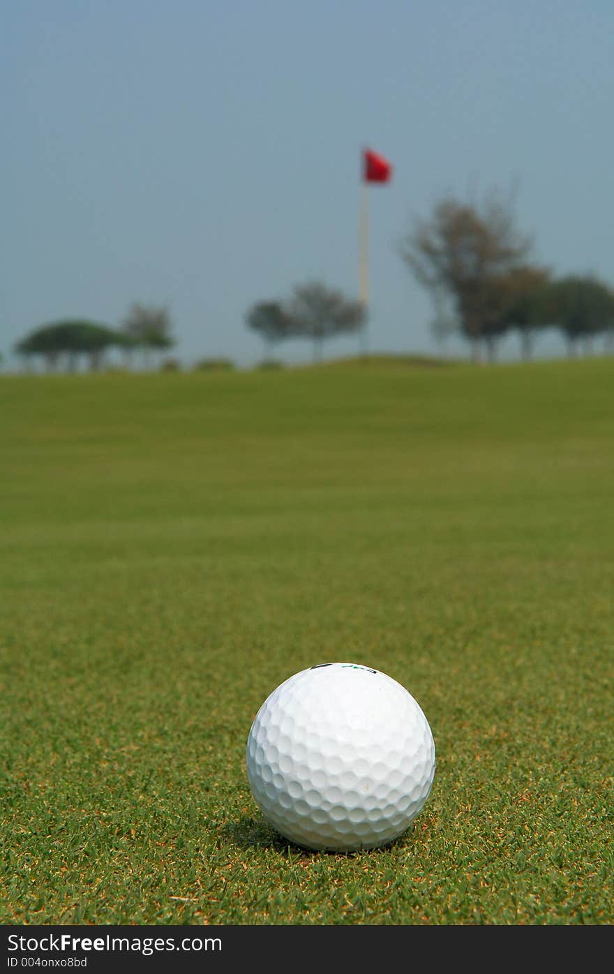 Golf ball with a flag pole in the background. Golf ball with a flag pole in the background