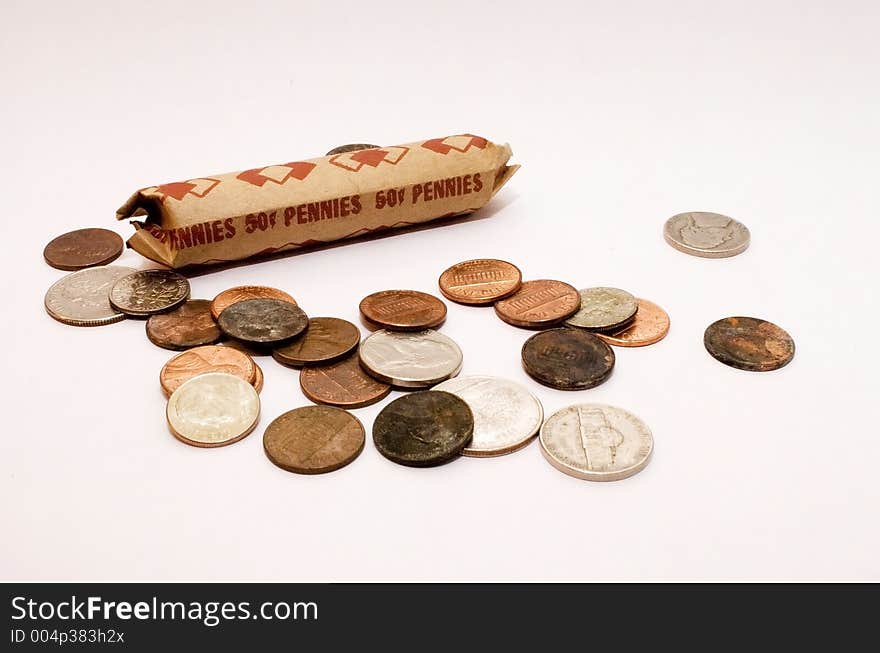 A roll of pennies sits among other American coins