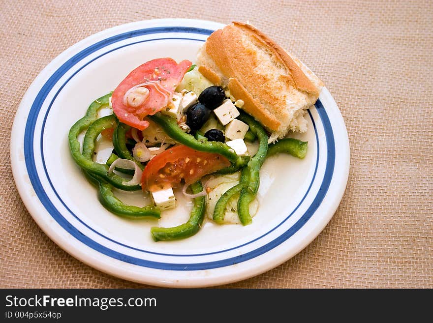 My version of a simple Greek salad with crusty french bread on old crockery plate. Horiatiki means village. My version of a simple Greek salad with crusty french bread on old crockery plate. Horiatiki means village.