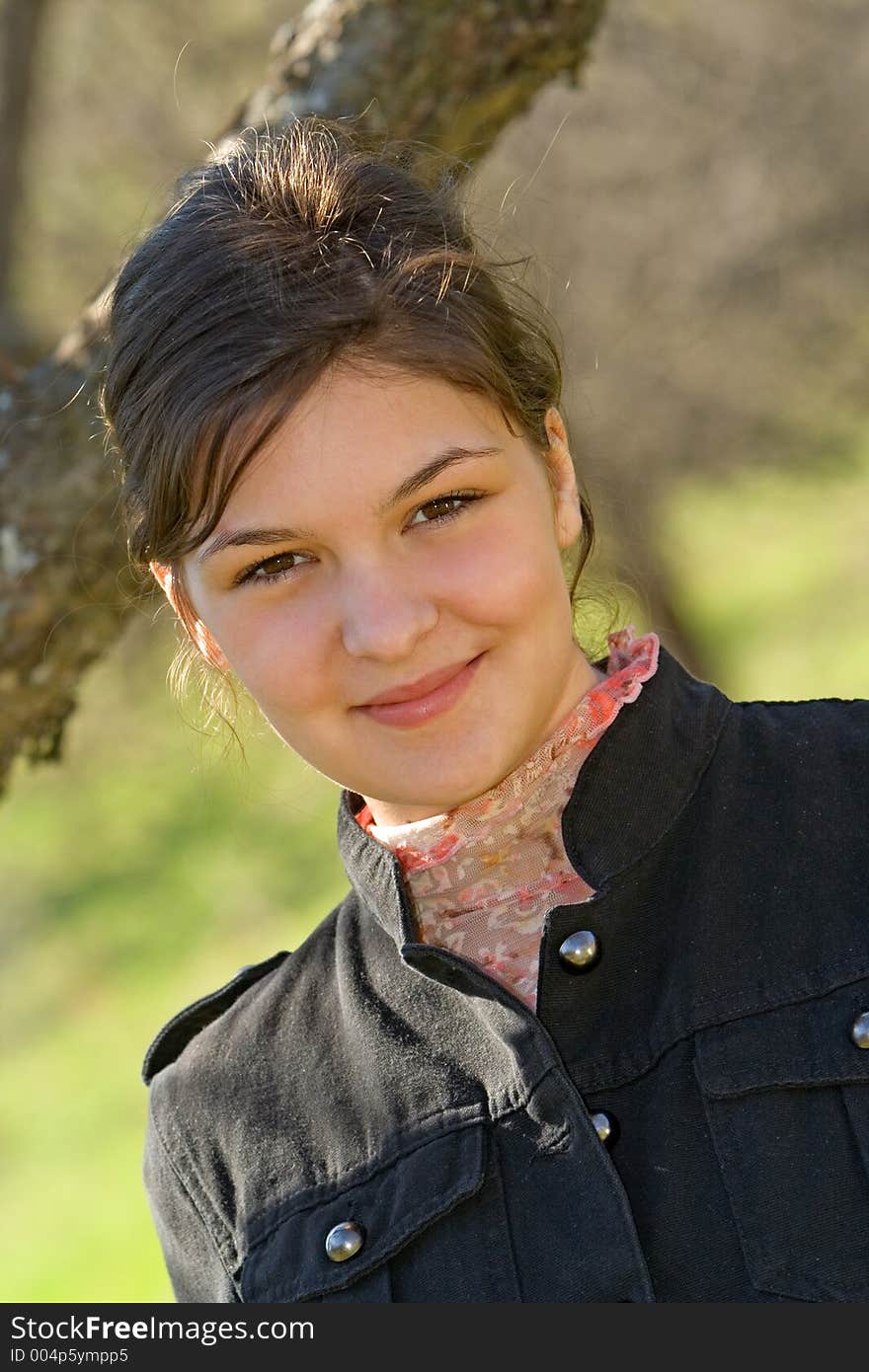 Young woman sitting beneath a tree smiling. Young woman sitting beneath a tree smiling