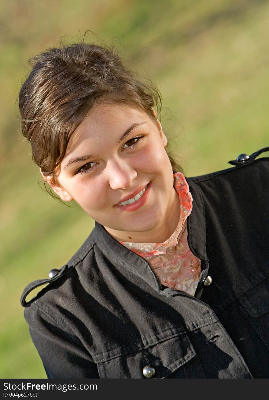 Young woman sitting beneath a tree smiling. Young woman sitting beneath a tree smiling