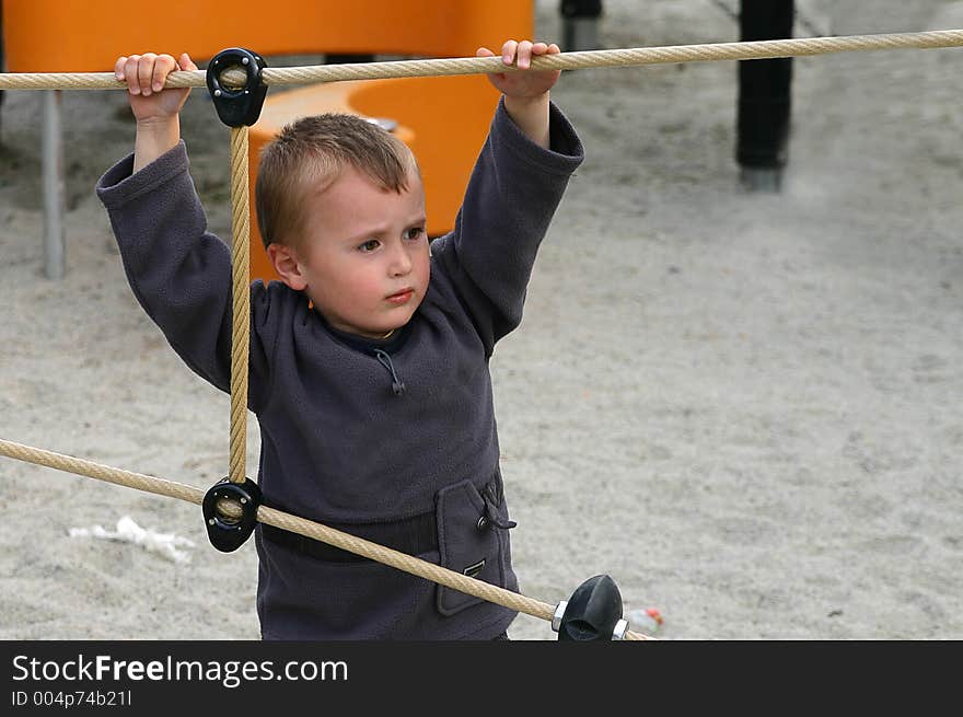 Little boy hanging on a rope in the park