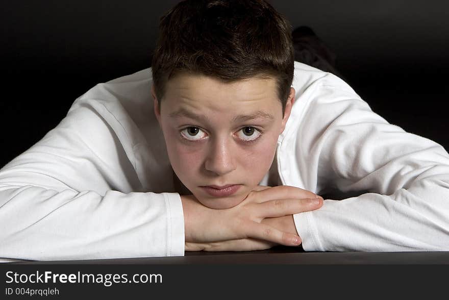 Teenage boy wearing white t shirt against plain black backdrop. Teenage boy wearing white t shirt against plain black backdrop