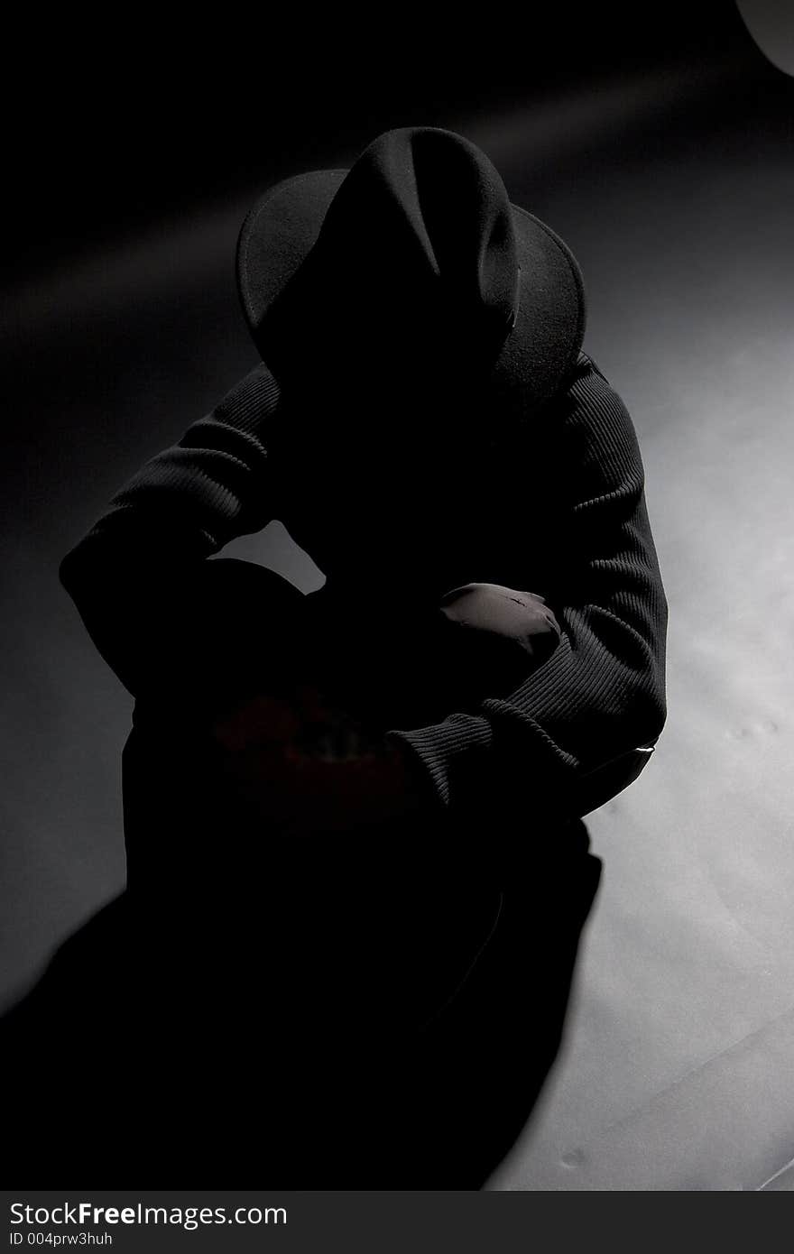 Dark showed shot of male model, sitting dressed totally inblack against a black backdrop. Dark showed shot of male model, sitting dressed totally inblack against a black backdrop