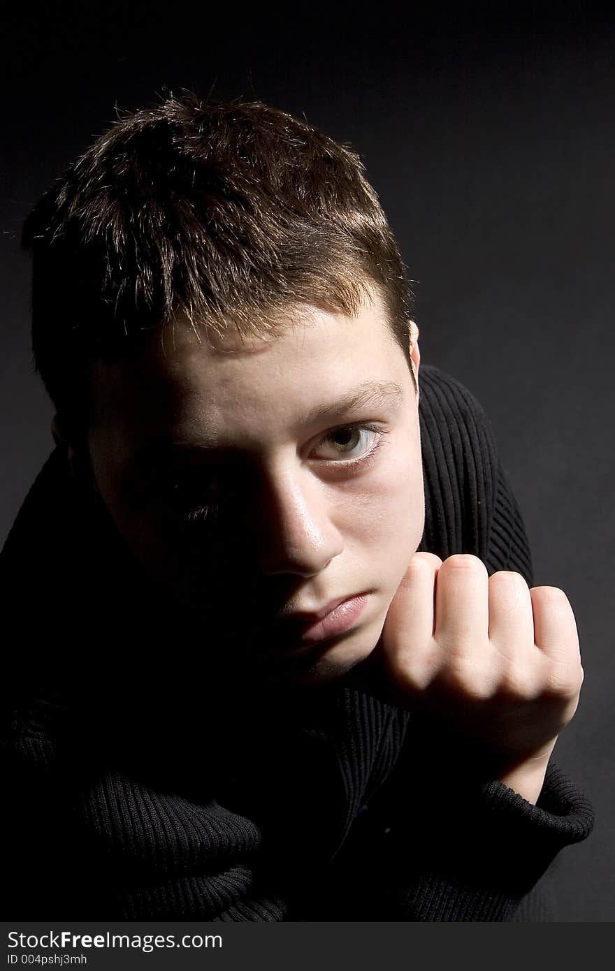 Teenager portrait looking up towards camera against black backdrop