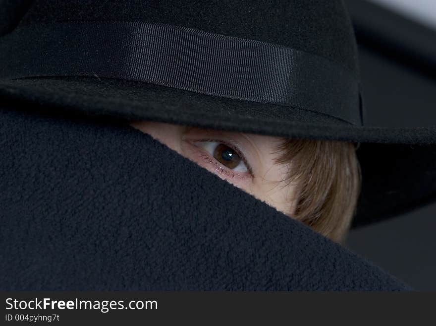 Unusual portrait of female model with dark hat and most of face covered only one eye showing. Unusual portrait of female model with dark hat and most of face covered only one eye showing