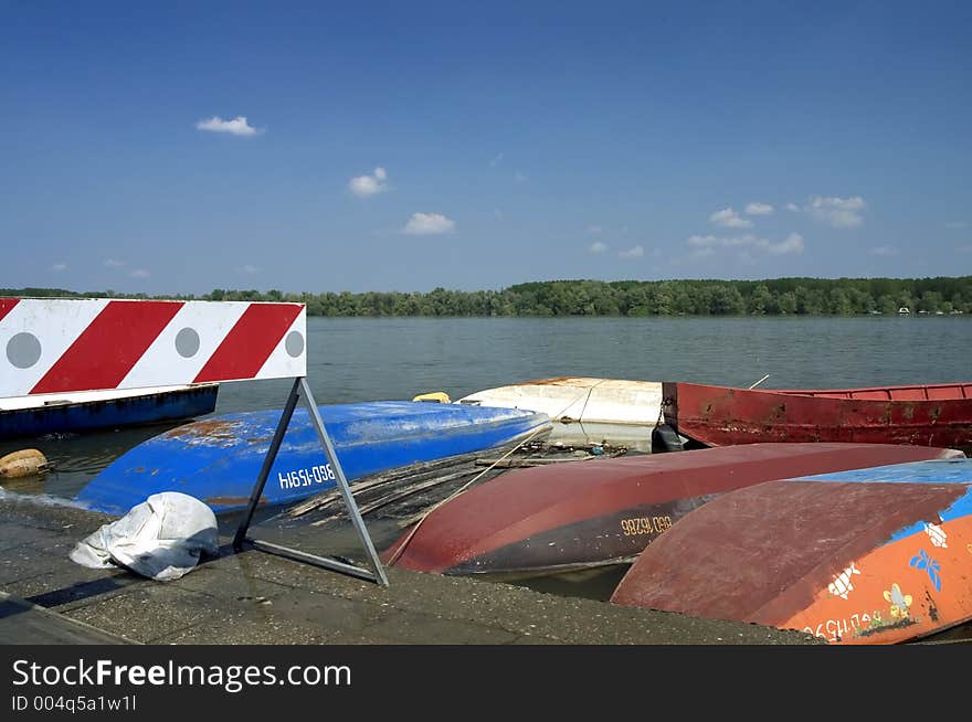 Road sign near the river and boats and sky in background. Road sign near the river and boats and sky in background