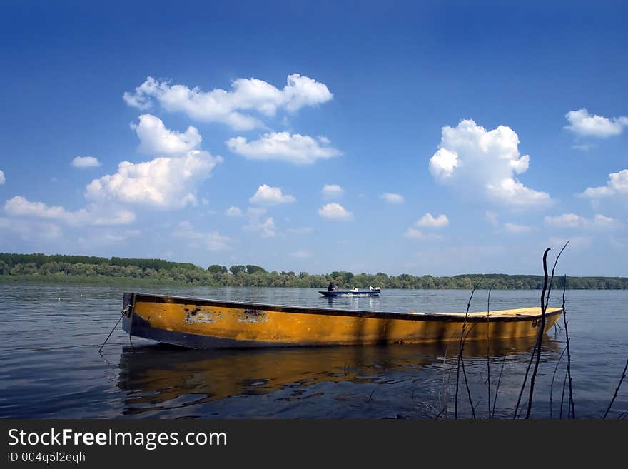 Riverscape with orange boat and sky with clouds in background